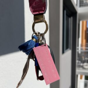 pink keychain with the lyrics "How we in my car and you say we ain't in the same lane," attached to a set of keys hanging